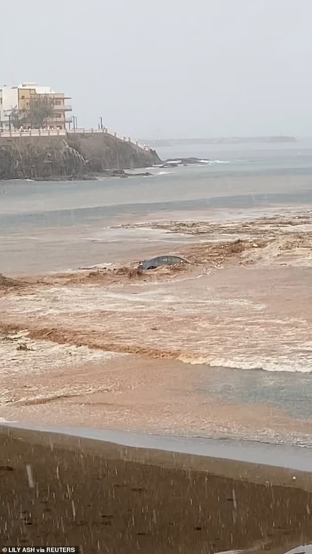 Chiếc xe bị đẩy ra biển bởi dòng nước màu đất chảy xiết.