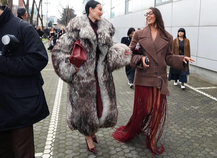 Qua nhiều mùa fashion week, áo lông là một phần không thể thiếu và đây là một chiếc áo lông thú nhân tạo dáng oversize với dải màu trắng và nâu đỏ siêu bắt mắt và quyền quý. Bộ trang phục này tiếp tục hoàn thiện với tông đỏ burgundy-tông màu siêu hot trong những năm gần đây.Bên cạnh chiếc áo lông chính là một nhân vật mang tính thời trang vintage. Đó là chiếc chân váy tua rua đỏ burgundy gợi nhắc đến thế kỉ 20. 