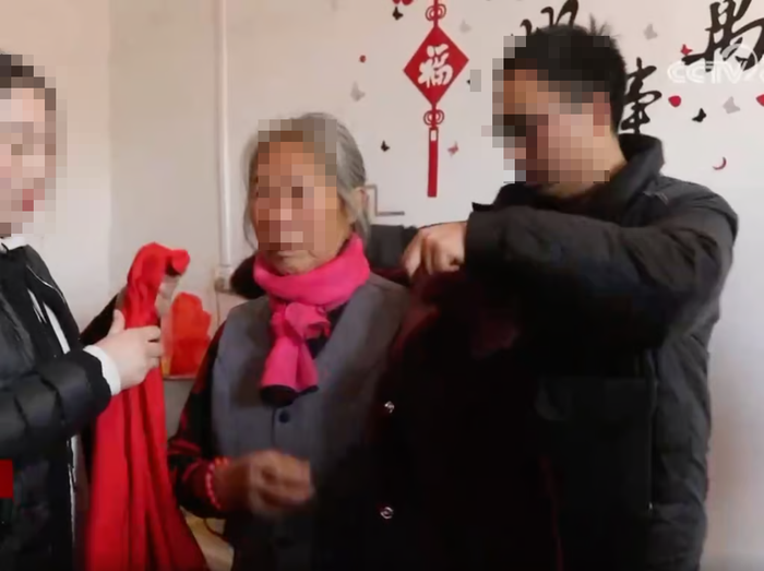 Zhang giúp người mẹ thất lạc từ lâu của mình mặc áo khoác sau cuộc đoàn tụ đầy cảm xúc.