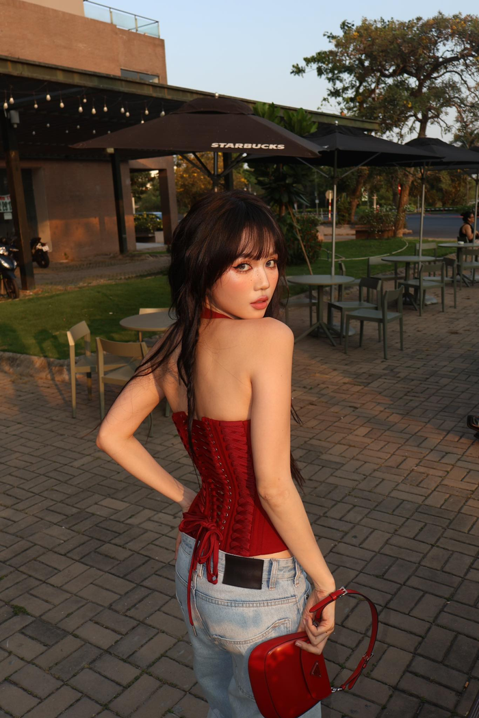 Trong loạt ảnh, Ngọc Trinh diện corset đỏ dáng halter cổ chữ V sâu kết hợp cùng quần jeans ống rộng cạp trễ - hai items đặc trưng của thập niên 2000 đang được giới trẻ “săn lùng” trở lại. 