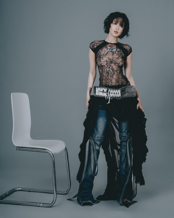 Trong lookbook mà Ngọc Trinh đăng trên instagram, cô đã diện một outfit mang hơi hướng Street style đầy quyến rũ và cá tính. Người đẹp chọn một chiếc áo ren đen xuyên thấu, tạo cảm giác vừa gợi cảm vừa táo bạo. Phần áo có tay ngắn, cổ cao và có một miếng dán có chữ như một điểm nhấn. Kết hợp với áo là chiếc quần jeans xanh đậm mang hơi hướng đường phố, được thêm các lớp vải và dây đai tạo nên sự phá cách. Điểm độc đáo trong trang phục là phần váy đen khoác ngoài quần jeans, làm tăng thêm sự mềm mại và chuyển động. 
