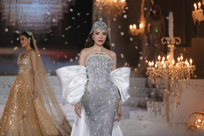 Ngoài Hoàng Thùy, show diễn còn có sự góp mặt của nhiều Hoa - Á hậu quen thuộc khác như Lê Hoàng Phương, Khánh Vân, Ngọc Châu. Hoa hậu Lê Hoàng Phương tỏa sáng lộng lẫy trong một bộ cánh dạ hội quyền lực. Điểm nhấn đầu tiên là chiếc mấn đội đầu được chế tác công phu, đính kết đá quý và pha lê dày đặc, ôm trọn phần trán và thái dương, mang lại vẻ vương giả và thu hút. Thiết kế váy cúp ngực ôm sát cơ thể được bao phủ hoàn toàn bởi hàng ngàn viên đá, pha lê và cườm bạc. 