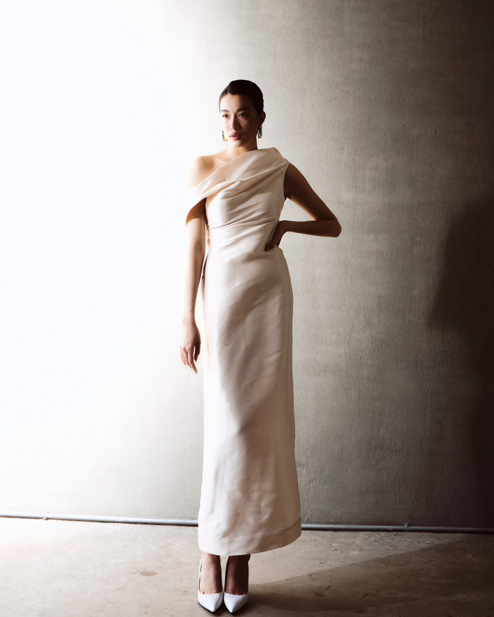 Bề mặt vải có độ sần, thô mịn, không hề phẳng mượt theo kiểu công nghiệp. Chính lớp texture nhẹ này khiến ta liên tưởng đến làn da sau tuổi 30 – không còn căng bóng nhưng lại ẩn chứa chiều sâu, lịch sử sống và cảm xúc.