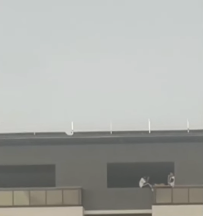 Hai thanh niên ngồi vắt vẻo trên ban công tòa nhà cao tầng trò chuyện, người đi đường thót tim Ảnh 2