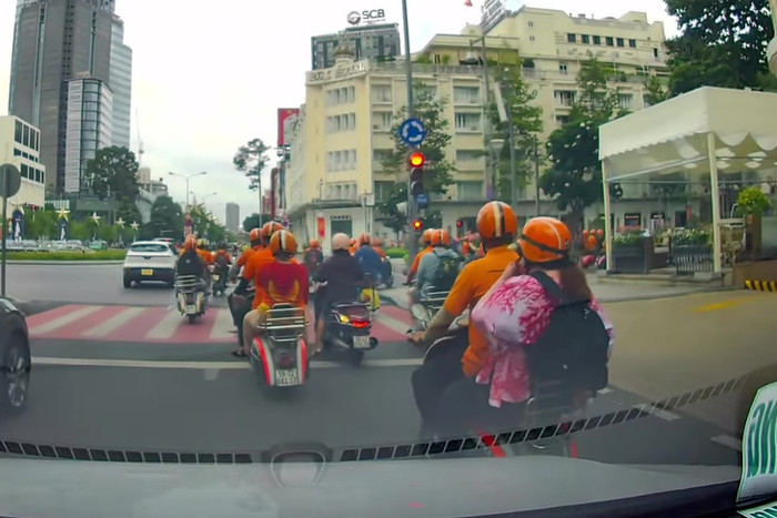 Đoàn xe Vespa cổ mặc áo cam bất chấp tín hiệu đèn đỏ, vẫn điều khiển xe vượt qua. Ảnh cắt từ clip 