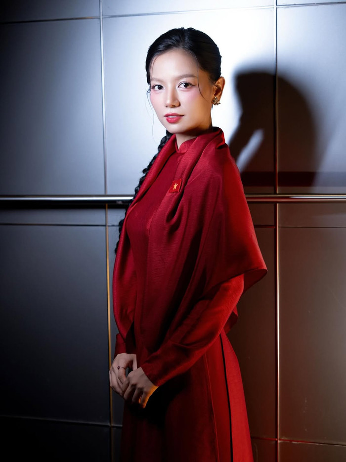 Không dừng lại ở tông màu nhẹ nhàng, Lê Hạ Anh cũng thử sức với áo dài đỏ rực rỡ - màu sắc biểu tượng cho sức sống và lòng tự hào dân tộc. Phụ kiện như khuyên tai vàng góp phần làm nổi bật gương mặt thanh tú. Ảnh: IGNV