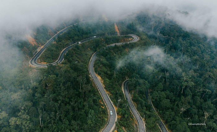 Đến với địa điểm này, cung đường dẫn lên chùa là một trải nghiệm đáng nhớ. Quãng đường đèo dài khoảng 37km với nhiều khúc cua uốn lượn liên tiếp, càng lên cao cảnh quan càng thay đổi rõ rệt: từ rừng thưa chuyển dần sang rừng nguyên sinh rậm rạp. Những ngày sương mù dày và mây trắng bao phủ, con đường như dẫn lối qua các tầng mây, mang đến cảm giác vừa phiêu du, vừa thử thách đối với du khách yêu khám phá. Ảnh: AmazingNha Trang