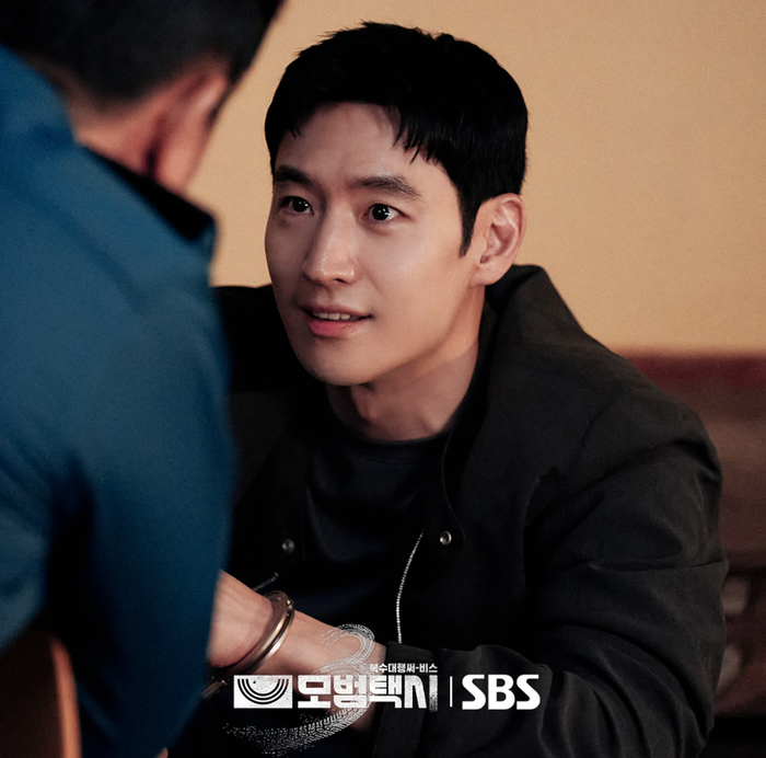 Lee Je Hoon trong still cut mới của Taxi Driver 3, bị còng tay nhưng ánh mắt đầy toan tính - Ảnh: SBS