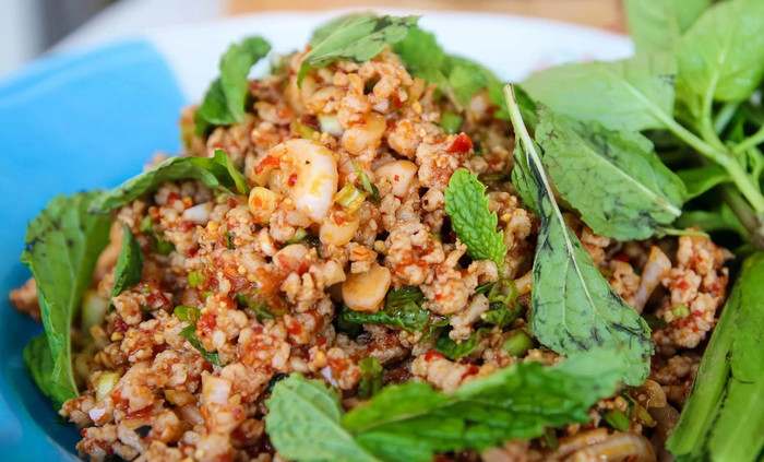 Tam Mak Hoong (gỏi đu đủ kiểu Lào) với hương vị vị mặn, cay và chút đắng đặc trưng của pa-daek — một trong những nguyên liệu linh hồn của ẩm thực Lào.