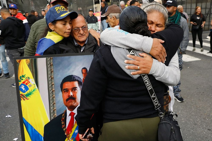 Những người ủng hộ Tổng thống Venezuela Nicolás Maduro ôm nhau ở trung tâm Caracas sau khi tổng thống bị Mỹ bắt giữ. (AP)