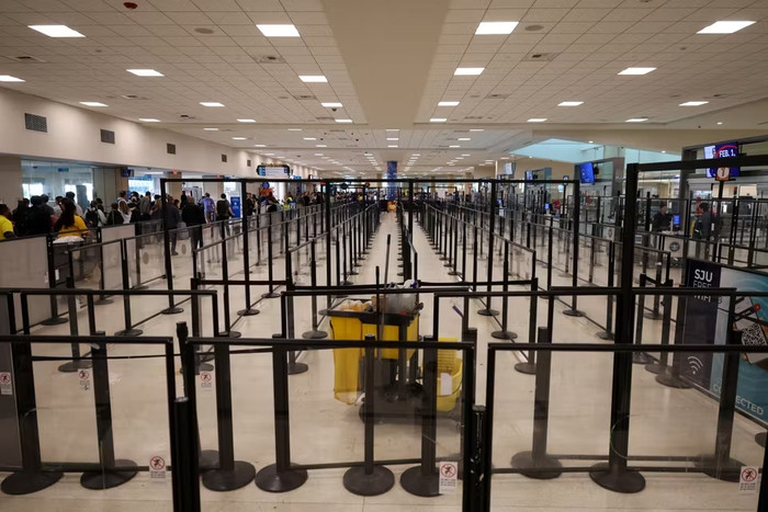 Hành khách đi bộ gần các rào chắn xếp hàng, sau khi các chuyến bay bị hoãn và hủy do không phận bị đóng cửa vì các cuộc tấn công của Mỹ vào Venezuela đêm trước đó, tại Sân bay Quốc tế Luis Munoz Marin ở Carolina, gần San Juan, Puerto Rico, ngày 3 tháng 1 năm 2026. RICARDO ARDUENGO / REUTERS