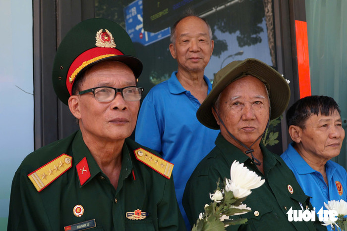 Ông Bùi Nam Từ (thứ nhất từ trái sang), cựu Chủ tịch Hội cựu chiến binh quận 3 (cũ), từng là chiến sĩ tham gia lái xe trên tuyến đường mòn Trường Sơn. Dù năm nay đã 74 tuổi nhưng từ sáng sớm ông đã có mặt tại Vòng xoay Dân chủ để đưa tiễn những người đồng đội.Khi đoàn xe đi qua, ông nghẹn ngào nói: “Tôi thấy thương những người đồng đội của mình lắm, những người đã ngã xuống, đánh đổi sự hi sinh để đem lại hòa bình cho tổ quốc. Tôi thương các đồng đội đã ngã xuống hơn 6 thập kỷ hôm nay đã được trở về nhà. Từ tối tôi đã chuẩn bị hoa và quần áo tươm tất để đến đây tiễn đưa họ về với đất mẹ”, ông Từ xúc động - Ảnh: ĐẶNG LINH&nbsp;