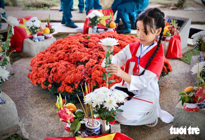 Bé My, một trong những em bé có mặt ở Nghĩa trang liệt sĩ TP.HCM hôm nay đang đặt những bông hoa cúc trắng lên phần mộ các liệt sĩ - Ảnh: NGUYỄN KHÁNH&nbsp;
