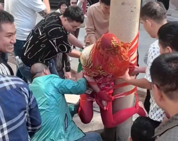 Làn sóng chỉ trích bùng lên sau khi video ghi lại cảnh một cô dâu Trung Quốc bị trói vào cột điện. Sự việc làm dấy lên cuộc tranh luận gay gắt về những trò trêu chọc quá đà trong đám cưới. Ảnh: Weibo.