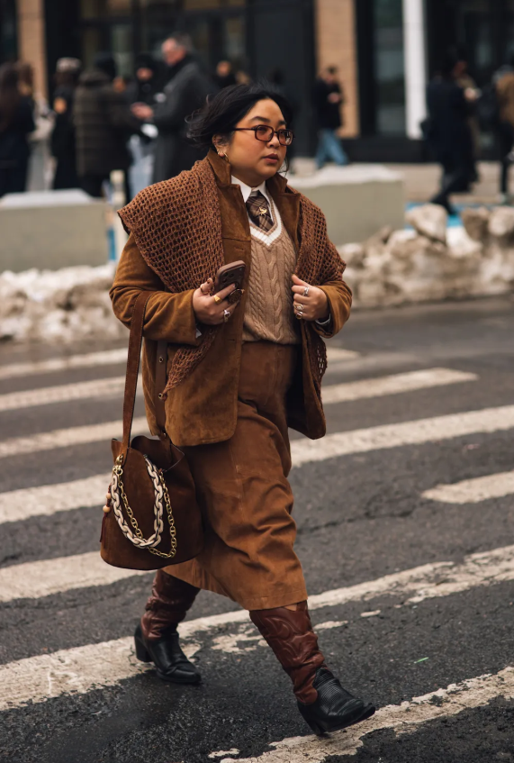 Những bộ đồ đồng bộ luôn mang lại cảm giác gọn gàng và chỉn chu ngay từ cái nhìn đầu tiên. Vị khách tham dự show lựa chọn set da lộn, phối boots cao bồi hai tông màu, nhấn nhá bằng cà vạt cài vest len và túi xô đính chi tiết kim loại nổi bật. Ảnh: Getty Images
