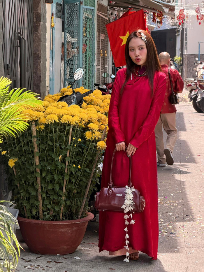 Phương Mỹ Chi rạng rỡ trong tà áo đỏ trơn mang không khí ngày Tết, chất liệu mềm rủ tạo độ bay nhẹ. Thiết kế tối giản nhưng nổi bật nhờ màu sắc, kết hợp phụ kiện tóc và túi xách nâu cổ điển tạo vẻ vừa ngọt ngào vừa cá tính. Ảnh: FBNV