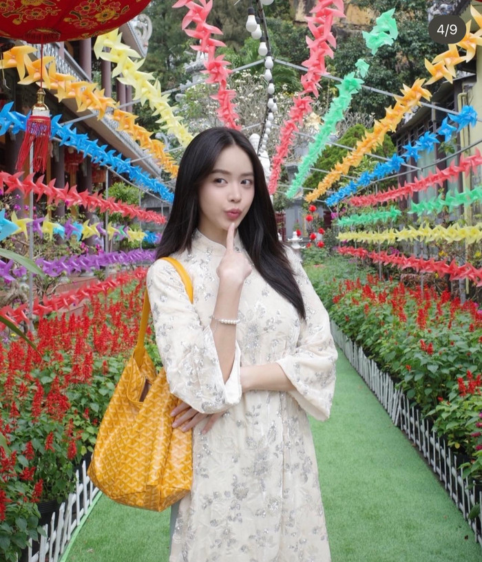 Hoa hậu Thanh Thủy lựa chọn thiết kế áo dài trắng ngà được phủ họa tiết thêu và đính sequin lấp lánh, tạo hiệu ứng bắt sáng nhẹ nhàng. Phom dáng suông cùng tay lỡ giúp tổng thể thanh thoát, thanh lịch và rất hợp không khí du xuân. Ảnh: FBNV