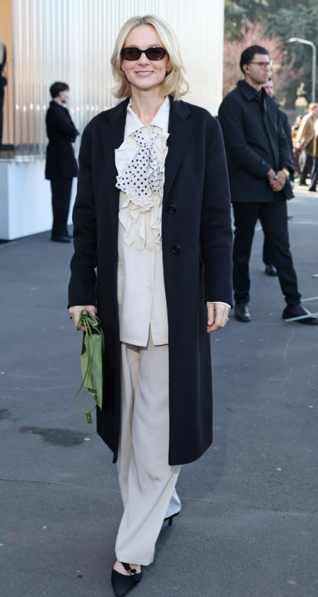 Carey Mulligan chọn set đồ tông kem gồm áo bèo nhún mềm mại và quần suông thanh thoát, khoác ngoài áo măng tô đen tối giản. Ảnh: Getty Images