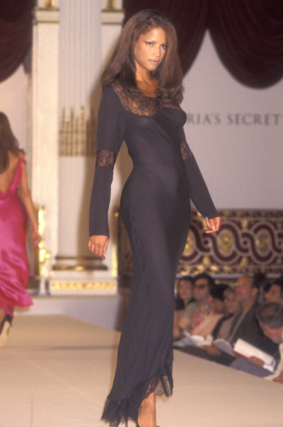 Tại show diễn Victoria’s Secret đầu tiên năm 1995, Veronica Webb đã khắc họa rõ nét tầm nhìn ban đầu của thương hiệu về vẻ gợi cảm tinh tế, trong chiếc váy slipdress đen xuyên thấu viền ren mảnh mai. Ảnh: Harpers Bazaar