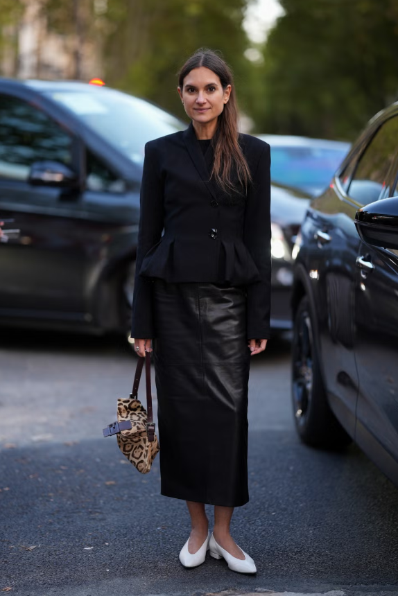 Áo blazer không chỉ là “bạn đồng hành” lý tưởng của quần jeans mà còn kết hợp ăn ý với chân váy midi thanh lịch. Để tạo điểm nhấn, hãy thử blazer dáng peplum, mang đến sự tương phản giữa phom váy midi da gọn gàng và phần thân trên có độ phồng mềm mại. Ảnh: Harpers Bazaar