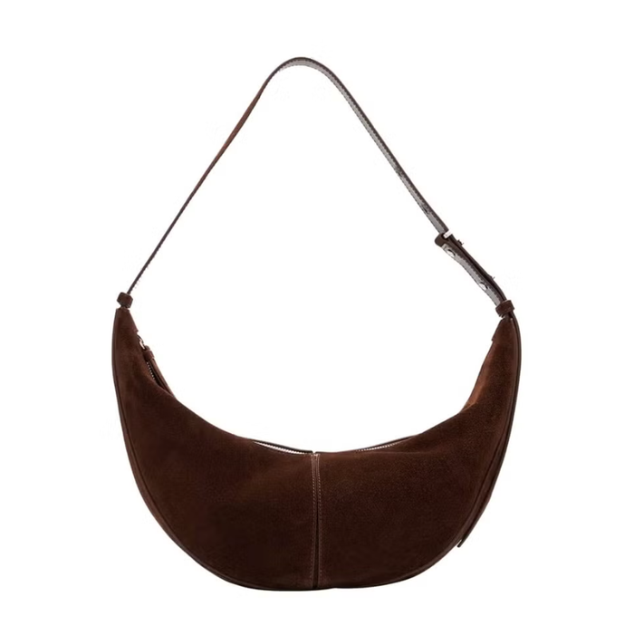 Với kiểu dáng cong mềm mại và chất liệu da lộn cao cấp, chiếc túi đeo vai của Proenza Schouler vừa mang vẻ đẹp vượt thời gian vừa tạo điểm nhấn nổi bật. Túi được trang trí bằng các đinh tán dọc theo quai đeo và họa tiết monogram ở đáy, tạo nên vẻ sang trọng tinh tế. Ảnh: Harpers Bazaar