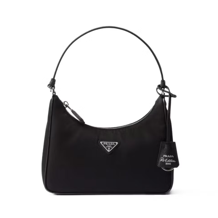 Chiếc túi đeo vai Prada Re-Edition 2005 lấy cảm hứng từ chiếc túi hobo mini biểu tượng của thương hiệu, được chế tác từ sợi nylon tái chế được sản xuất từ ​​rác thải nhựa đã qua xử lý, thu gom từ đại dương, lưới đánh cá nổi và sợi phế thải dệt may. Túi còn được tô điểm thêm bằng viền da Saffiano. Ảnh: Harpers Bazaar