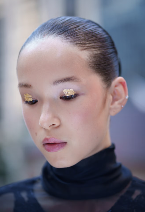 Sắc vàng ánh kim là xu hướng trang điểm mắt “hot” nhất hiện tại. Tại show của Prabal Gurung, những nhũ vàng li ti được điểm xuyết tinh tế trên mí mắt, tạo nên sự cân bằng hoàn hảo với hàng mi gần như để mộc, lớp nền tự nhiên và đôi môi hồng nhạt. Xu hướng này cũng xuất hiện tại Collina Strada. Ảnh: Matteo Scarpellini