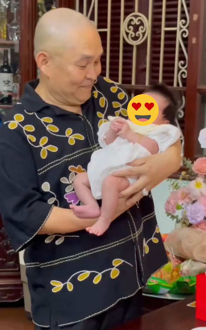 Nghệ sĩ Xuân Hinh bế cháu ngoại khi làm tiệc đầy tháng cho cô bé. Ảnh: anan.nhakhoai