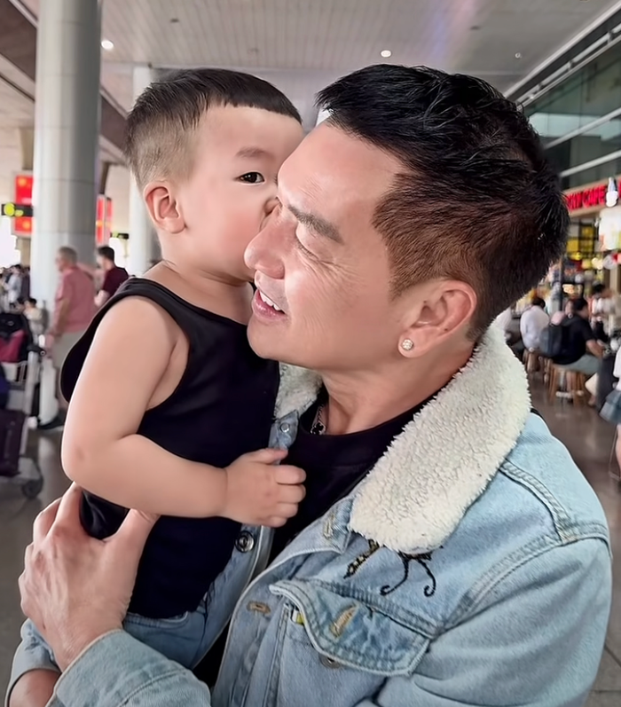 Nghệ sĩ Quang Minh xúc động ôm con sau một thời gian đi biểu diễn ở nước ngoài vào dịp Tết Nguyên đán. Ảnh: FBNV