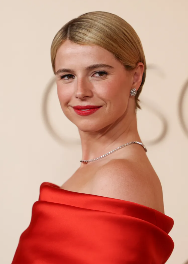 Nữ diễn viên Jessie Buckley lựa chọn kiểu tóc pixie vuốt gọn sang một bên. Nhà tạo mẫu Bryce Scarlett đã sử dụng nhiều sản phẩm tạo kiểu của Nexxus để giữ nếp tóc bóng mượt. Kiểu tóc gọn gàng giúp tôn lên bộ trang phục màu hồng đỏ đầy cá tính của Chanel.