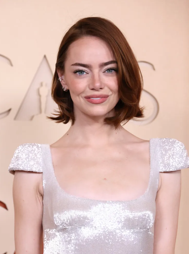 Emma Stone gây ấn tượng với mái tóc bob cổ điển được làm mới bởi chuyên gia nhuộm tóc nổi tiếng Tracey Cunningham. Kiểu tóc bob với phần ngôi lệch và đuôi tóc uốn nhẹ tạo cảm giác bồng bềnh, hài hòa với thiết kế váy cap-sleeve thanh lịch của Louis Vuitton. Nhà tạo mẫu tóc Mara Roszak đã sử dụng dụng cụ tạo kiểu của ghd để mang lại độ cong mềm mại cho phần đuôi tóc.