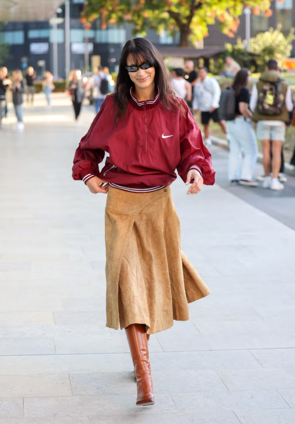 Heritage sportswear trở lại mạnh mẽ nhờ các nhà mốt như Miu Miu, Lacoste, Area hay Issey Miyake. Bella Hadid là minh chứng điển hình: cô phối jacket thể thao màu sắc nổi bật với chân váy da lộn và bốt da cao gối màu nâu, tạo sự cân bằng thú vị giữa nét sporty và chất liệu giàu kết cấu, nâng cấp bộ đồ thể thao truyền thống thành statement look mùa xuân. Ảnh: Getty Images