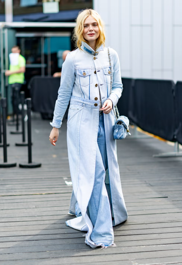 Elle Fanning mang đến phiên bản denim sang trọng với áo khoác cao cổ dài và quần jeans suông phủ sàn. Set đồ nhấn nhá với túi patchwork denim của Coach, tạo twist tinh tế cho phong cách “Canadian tuxedo” kinh điển, chứng minh rằng jeans từ cơ bản có thể trở thành statement look nếu biết cách mix layer và chọn phụ kiện. Ảnh: Getty Images