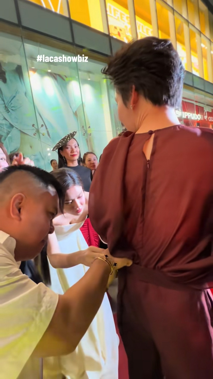 Quang Trung được Trương Quỳnh Anh chỉnh lại trang phục sau khi gặp sự cố rơi tà áo trên thảm đỏ. Ảnh: Ảnh: lacshowbiz