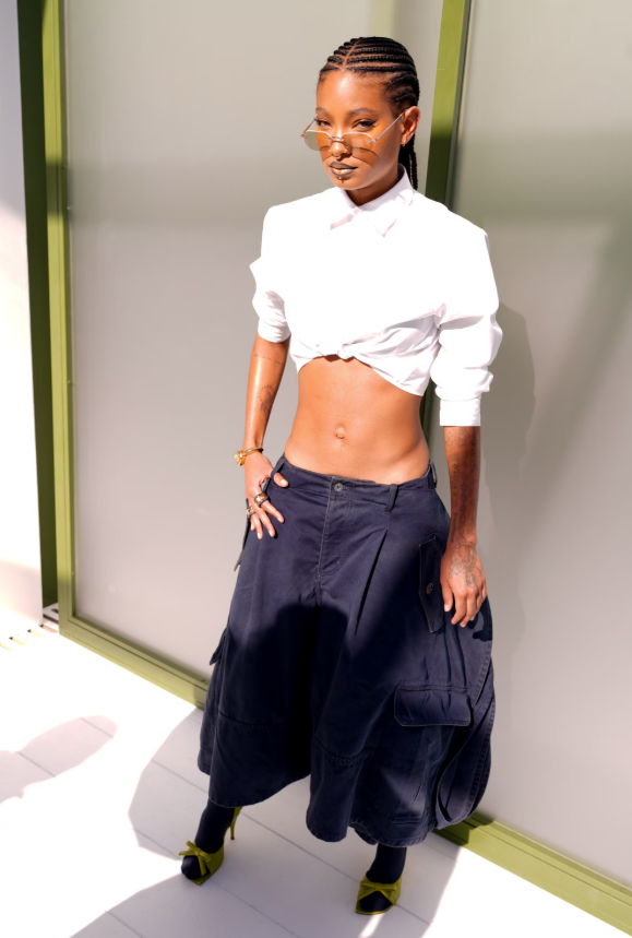 Willow Smith diện áo sơ mi trắng biến tấu croptop, phối cùng chân váy midi dáng rộng có túi hộp. Kính mắt nhỏ và giày cao gót màu nổi tạo điểm nhấn edgy, hiện đại và cá tính. Ảnh: Getty Images