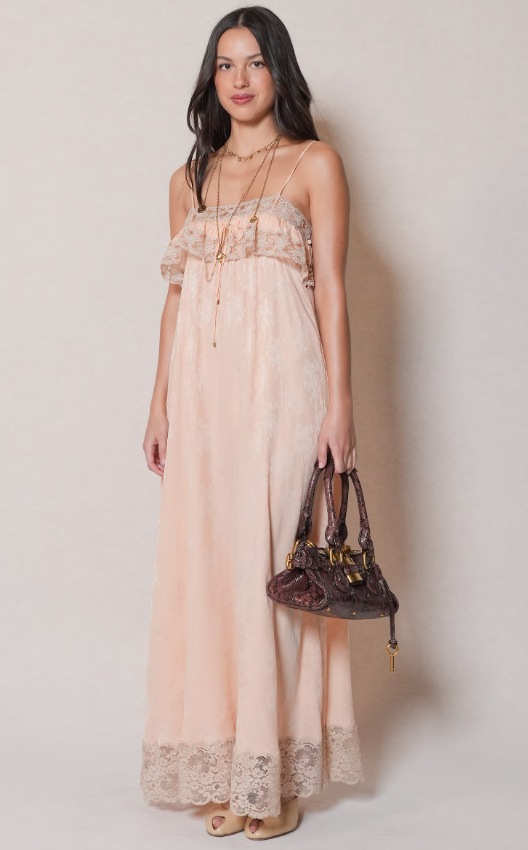 Olivia Rodrigo tham dự show Thu/Đông 2026 của Chloé trong chiếc váy maxi màu nude với dây mảnh và chi tiết ren tinh tế. Cô phối cùng vòng cổ dài và túi xách nhỏ, tạo vẻ nữ tính, mềm mại. Ảnh: Getty Images