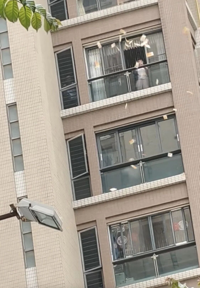 Người phụ nữ ném xấp tiền mặt từ ban công chung cư, người dân tranh nhau nhặt Ảnh 1