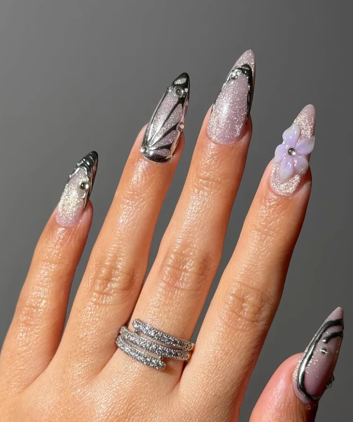 Hunter Schafer trong vai Jules nổi bật với phong cách “fairy-princess meets cyberpunk”, được tái hiện qua bộ nail đính bướm nhỏ xinh, phủ nhũ tím lấp lánh, điểm xuyết chrome kim loại mạnh mẽ.