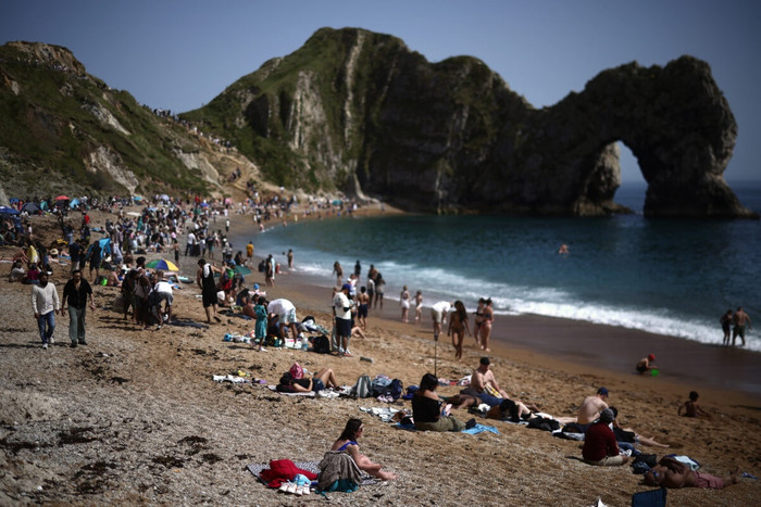 Người dân thư giãn dưới ánh nắng mặt trời trên bãi biển Durdle Door, phía đông Weymouth trên bờ biển phía nam nước Anh vào ngày 23 tháng 5 năm 2026, khi nhiệt độ dự kiến ​​sẽ tăng cao trong kỳ nghỉ lễ dài ngày cuối tuần. (Ảnh: Agence France-Presse)
