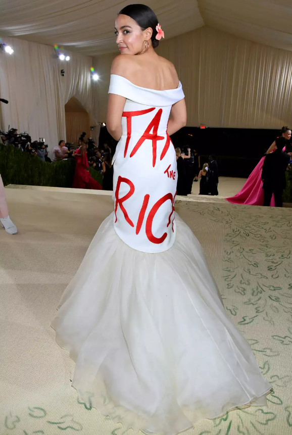 Tại Met Gala 2021, Alexandria Ocasio-Cortez gây chú ý khi diện váy trắng của Brother Vellies với thông điệp “Tax the Rich” nổi bật phía sau. Bà cho biết lựa chọn này nhằm thúc đẩy thảo luận về sự công bằng và bình đẳng trong xã hội. Ảnh: Getty