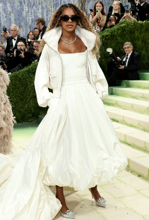 Blue Ivy Carter đã đến dự Met Gala cùng bố mẹ, Beyoncé và Jay-Z, trong lần đầu tiên bước lên bậc thang của Met Gala. Trong lần ra mắt này, cô bé diện một bộ trang phục Balenciaga toàn màu trắng gồm một chiếc váy dạ hội trắng dài đến đầu gối với phần đuôi váy dài thướt tha, kết hợp với một chiếc áo khoác trắng bên ngoài. Ảnh: Getty