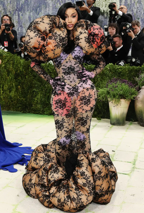 Cardi B xuất hiện muộn tại Met Gala 2026 trong một bộ trang phục thiết kế riêng của Marco Jacobs. Chiếc váy ren xếp tầng cầu kỳ của cô được mặc ngoài một bộ bodysuit phối màu. Cô hoàn thiện vẻ ngoài của mình với đôi bốt đế cao 23 cm. Ảnh: Getty