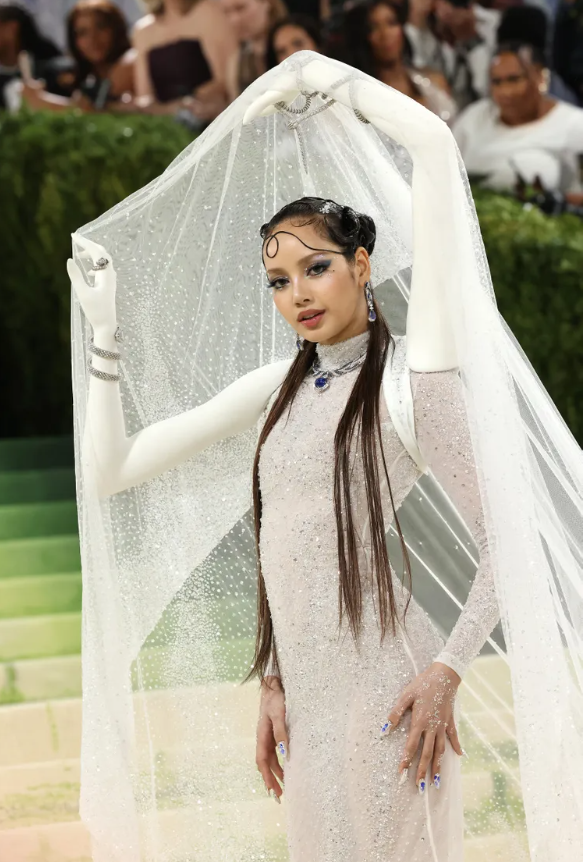 Thành viên Blackpink xuất hiện trên bậc thang Met Gala trong thiết kế váy của Robert Wun, được gắn thêm hai cánh tay phụ để nâng phần mạng che mặt. Chi tiết này gây chú ý vì tính sáng tạo và táo bạo. Dù mang yếu tố gây tranh cãi về tính ứng dụng, thiết kế vẫn tạo hiệu ứng thị giác mạnh mẽ và thu hút sự quan tâm từ truyền thông thời trang. Ảnh: Getty Images