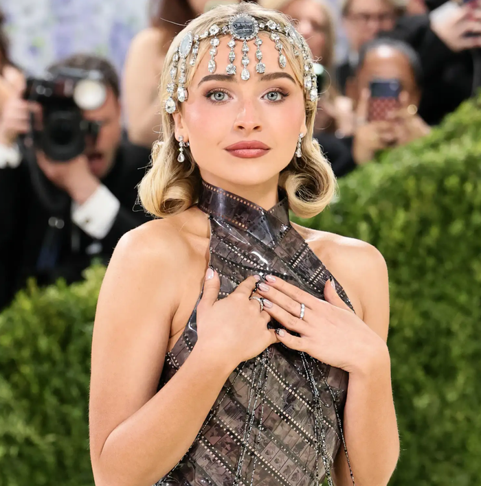Sabrina Carpenter gây ấn tượng với chiếc váy làm từ các dải phim đính rhinestone, tái hiện những cảnh trong bộ phim Sabrina (1954). Cô còn kết hợp loạt trang sức Chopard, gồm hai dây chuyền kim cương 50 carat, hoa tai 10 carat và phụ kiện đội đầu đính đá lấp lánh. Ảnh: FilmMagic