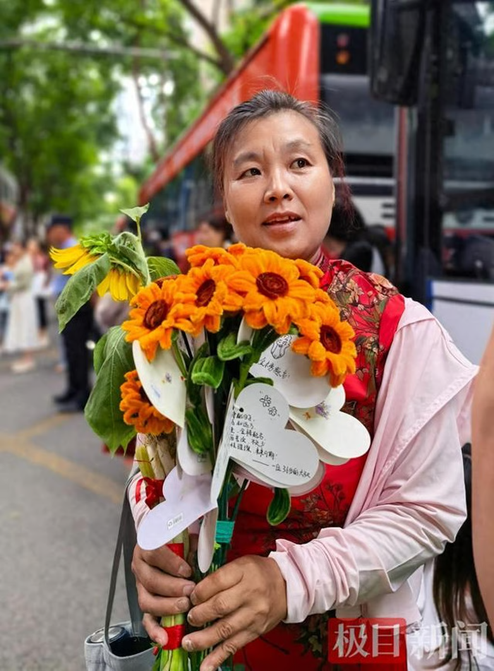 Bà Ye Huanzhi (ảnh trên), mẹ nuôi của Lele, đứng chờ bên ngoài địa điểm thi với bó hoa trên tay. Ảnh: Jimu News.