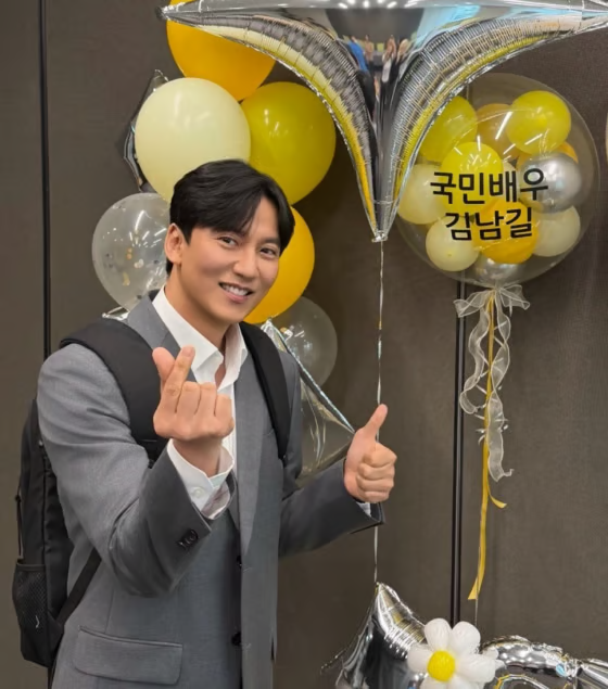 Kim Nam Gil tươi cười tạo dáng bên bóng bay mang dòng chữ 'Diễn viên Quốc dân Kim Nam Gil'. Nguồn: StarnewsKorea)