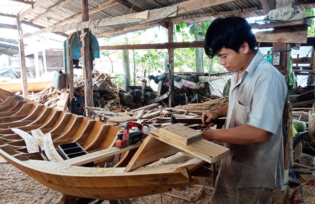 Người thợ dùng kinh nghiệm và đôi tay khéo léo để hoàn thành chiếc xuồng gỗ. Ảnh: báo Đồng Tháp