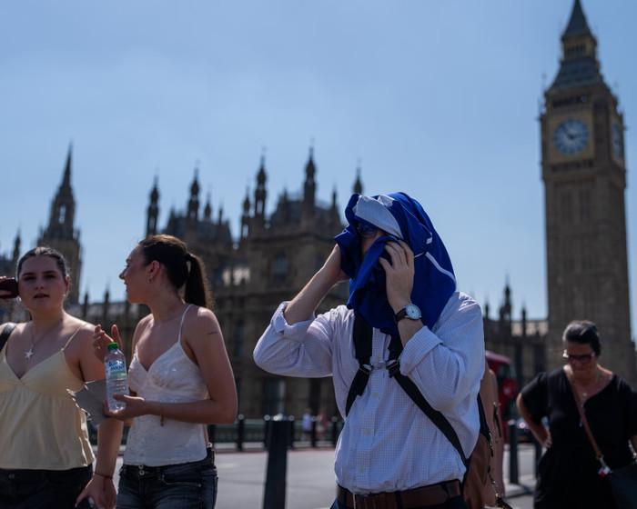 Một người đàn ông lấy áo phông che đầu để tránh nắng khi đi bộ qua trung tâm London. Ảnh: Carl Court/Getty Images&nbsp;