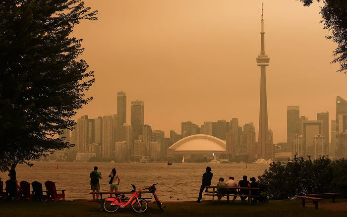 Người dân ngắm nhìn đường chân trời Toronto từ quần đảo Toronto trong bối cảnh khói từ các vụ cháy rừng ở miền bắc Ontario ảnh hưởng đến chất lượng không khí trong thành phố. (Ảnh AFP)