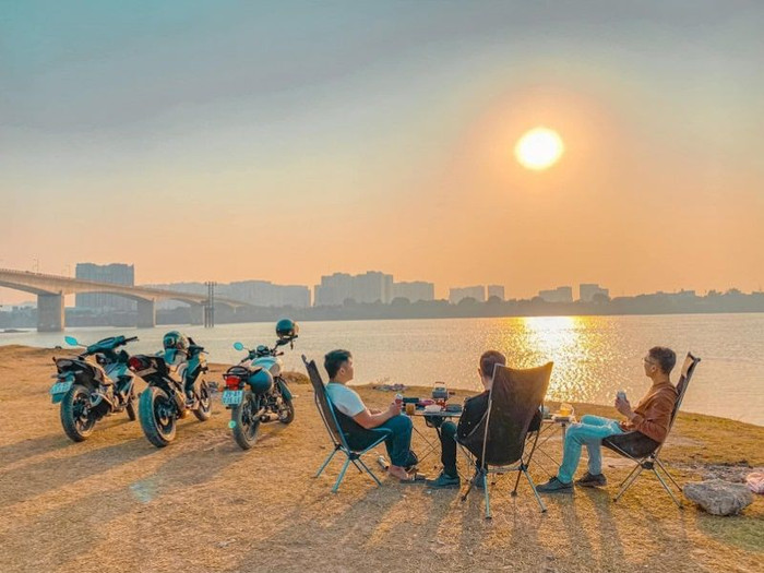 Các bạn trẻ ngắm hoàng hôn dưới chân cầu Vĩnh Tuy. Ảnh: Halo Travel&nbsp;